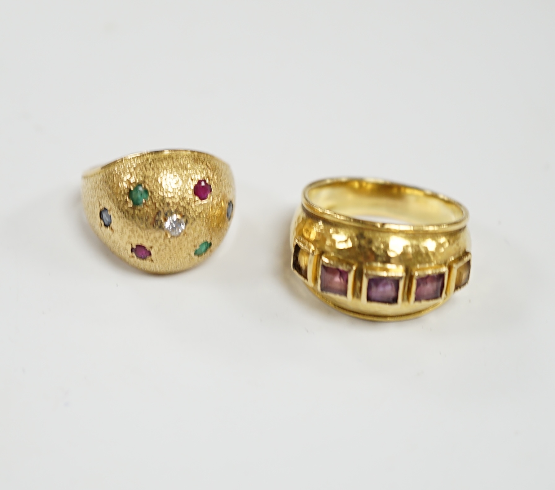A textured yellow metal, emerald, ruby and diamond set domed ring, size K, together with a stylish yellow metal and graduated square cut amethyst set five stone ring, size M, gross weight 13.1 grams.